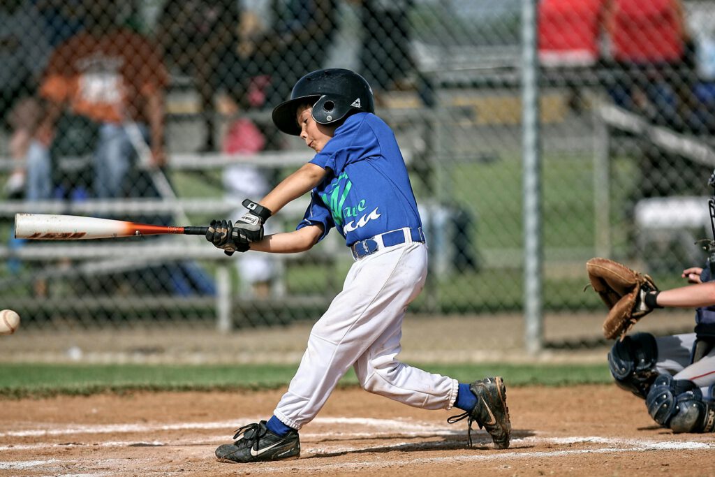 Best Snacks for Busy Parents 1 A young boy in a baseball uniform swinging a bat during a game, highlighting the need for convenient and nutritious snacks for busy parents and active kids.