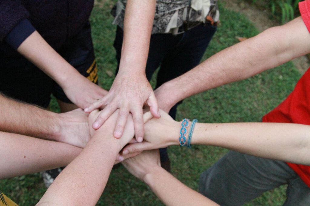 What Makes a “Complete Protein” in a Kids Snack? 2 A group of children and adults putting their hands together in a circle, symbolizing unity and the concept of complete protein in kids’ snacks.
